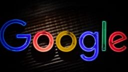 A neon sign displays the word Google in colorful, illuminated letters against a dark background.