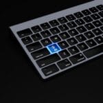 Partial view of a keyboard with a highlighted blue key labeled AI featuring a hand icon, set against a black background.