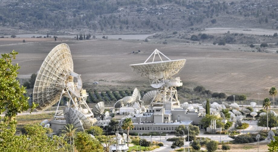 A satellite communication facility with multiple large and small satellite dishes in a rural landscape.