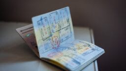 An open passport showing multiple immigration stamps on its pages, placed on a white surface.