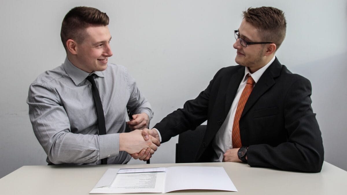 two men facing each other while shake hands and smiling