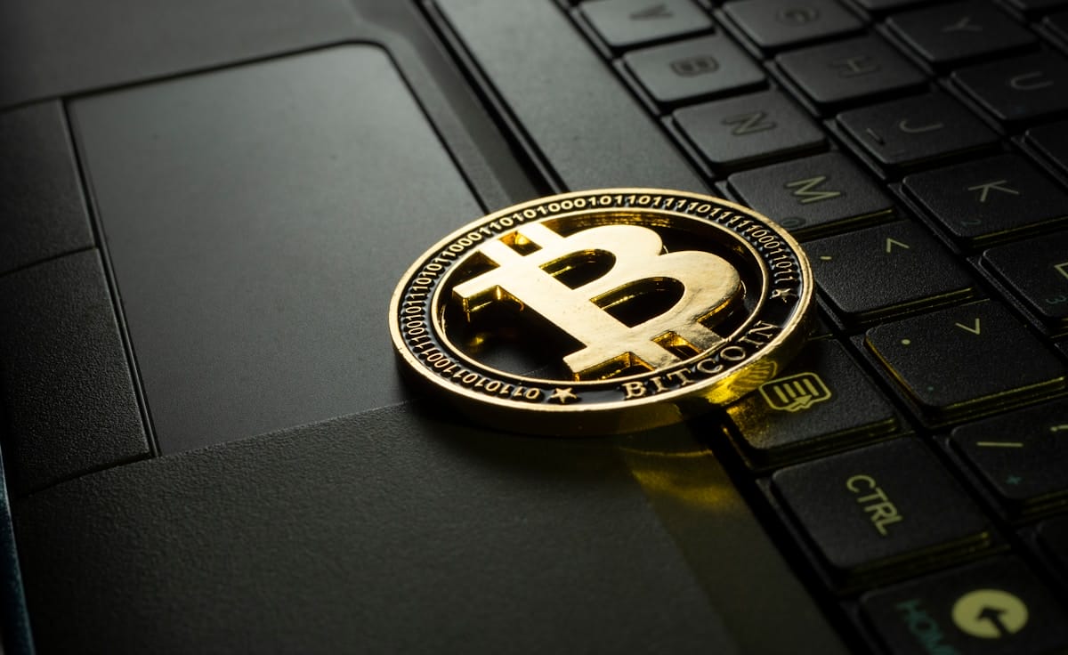 A gold Bitcoin token placed on a laptop keyboard, symbolizing cryptocurrency and digital transactions.