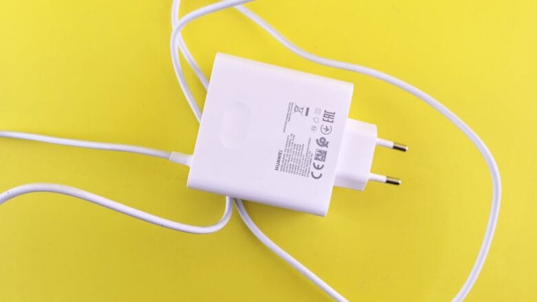 A white USB wall charger with a European plug and cable is placed on a yellow background.