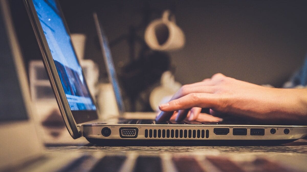 person using silver laptop computer on desk