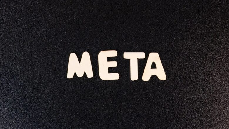 The word META spelled out in white wooden letters on a textured black background.