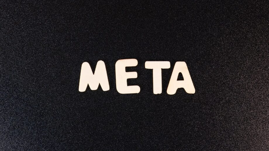 The word META spelled out in white wooden letters on a textured black background.