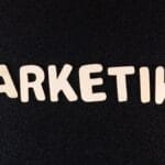 The word MARKETING spelled out in white capital letters on a black textured background.