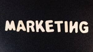 The word MARKETING spelled out in white capital letters on a black textured background.