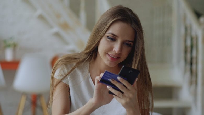 Young woman holding credit card and smartphone