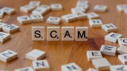 Scam spelled with scrabbles on a wooden table