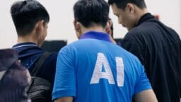 A group of people are standing together, with one person wearing a blue shirt labeled AI on the back.