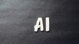 Wooden letters spelling AI placed on a dark, textured background.