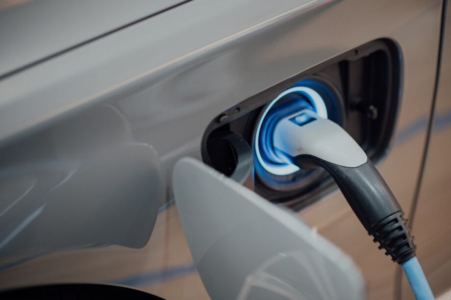 Close-up of an electric vehicle being charged, with the charging cable connected to the cars charging port.