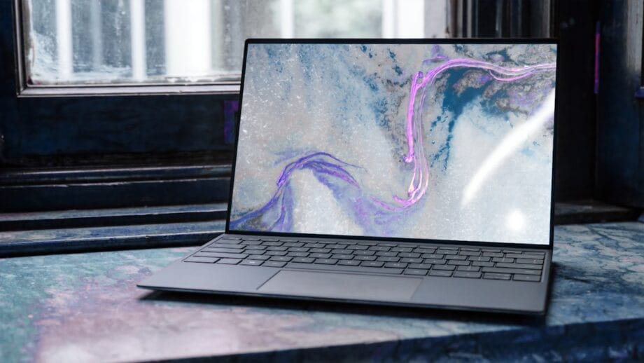 A laptop with a marble-patterned screen is placed on a marble windowsill next to a window.