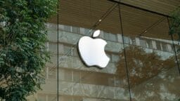 the apple logo is reflected in the glass of a building