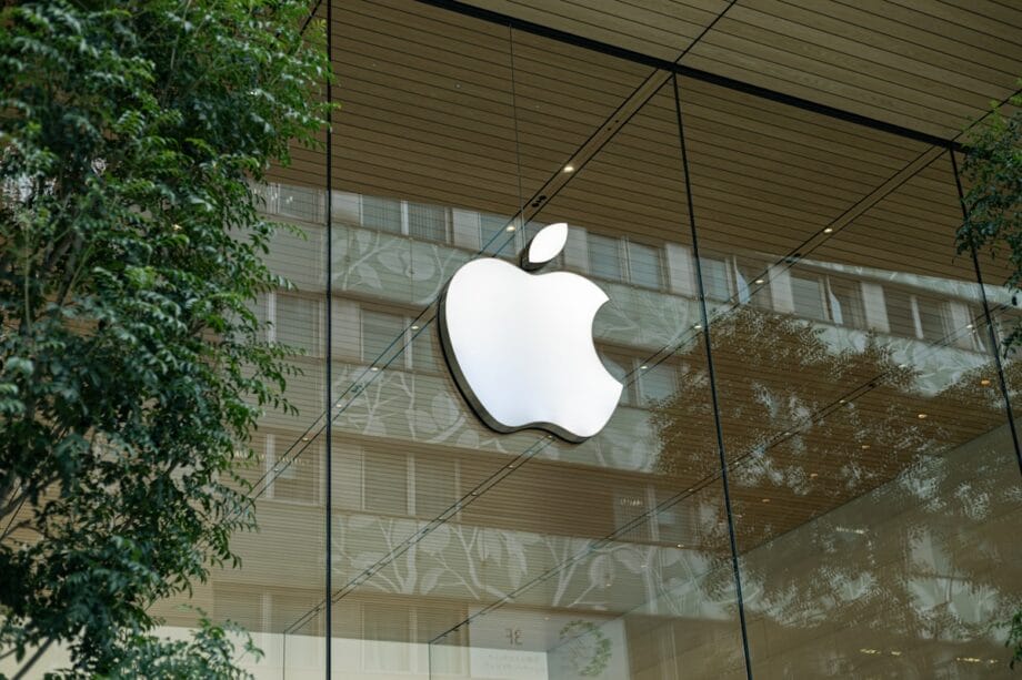 the apple logo is reflected in the glass of a building