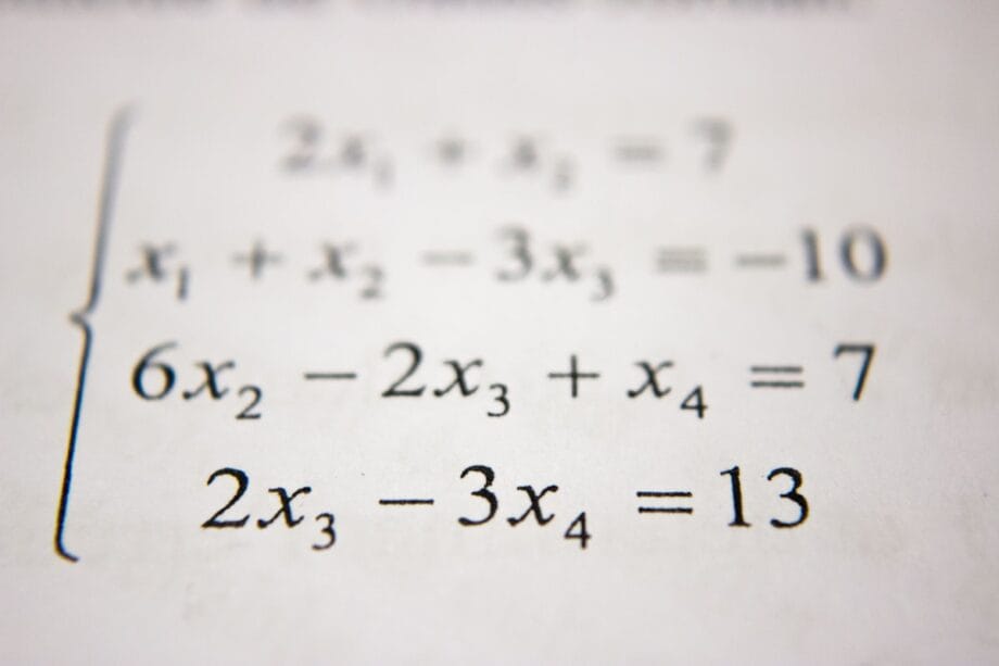A close-up of a printed system of linear equations with four variables and three equations.