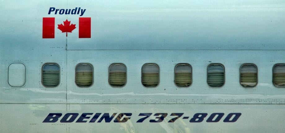 Close-up of a Boeing 737-800 airplane side with windows, Canadian flag, and Proudly text above the aircraft model name.
