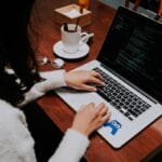 a woman using a laptop computer on a wooden table