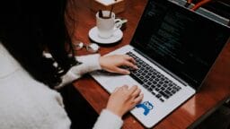 a woman using a laptop computer on a wooden table