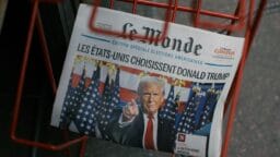 A Le Monde newspaper headline announces Donald Trump’s election win with his photo, displayed in a red wire rack.