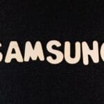 Wooden letters spelling SAMSUNG arranged on a black, textured surface.