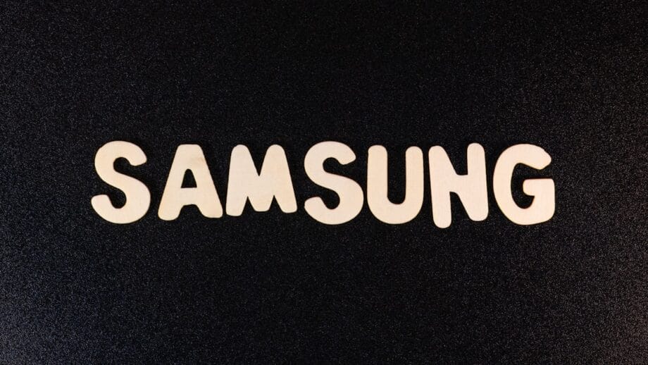 Wooden letters spelling SAMSUNG arranged on a black, textured surface.