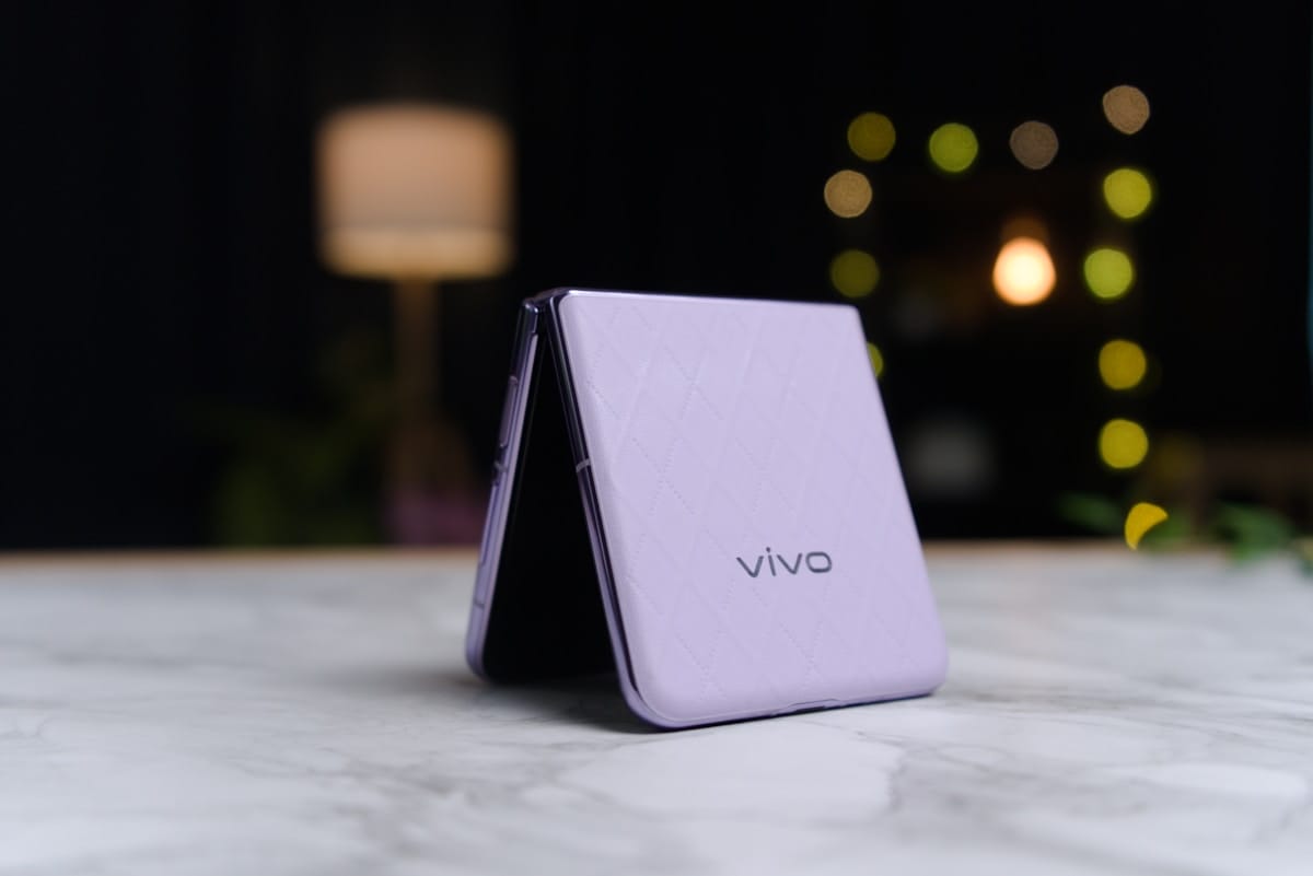 A purple Vivo foldable smartphone is standing upright on a marble surface with a blurred background.