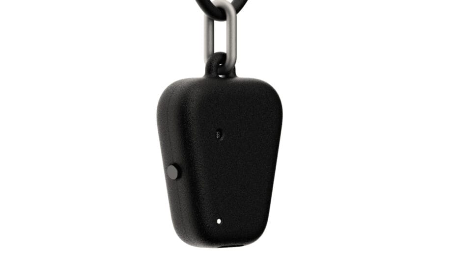 Close-up of a small, black, Fieldy device with a button and two small holes, attached to a metal keychain.