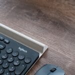 A close-up of a Logitech keyboard and mouse on a wooden desk.