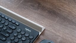 A close-up of a Logitech keyboard and mouse on a wooden desk.