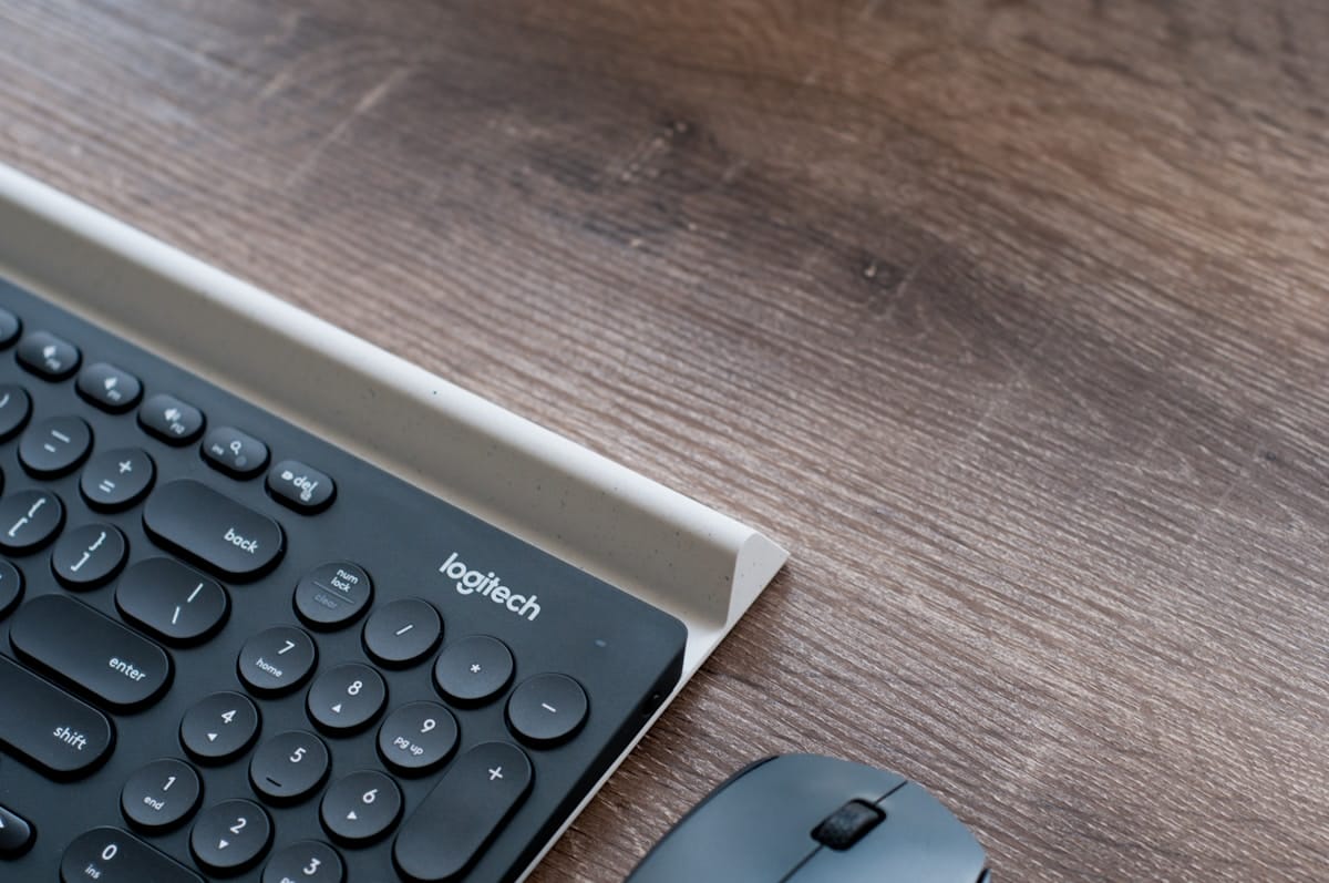 A close-up of a Logitech keyboard and mouse on a wooden desk.