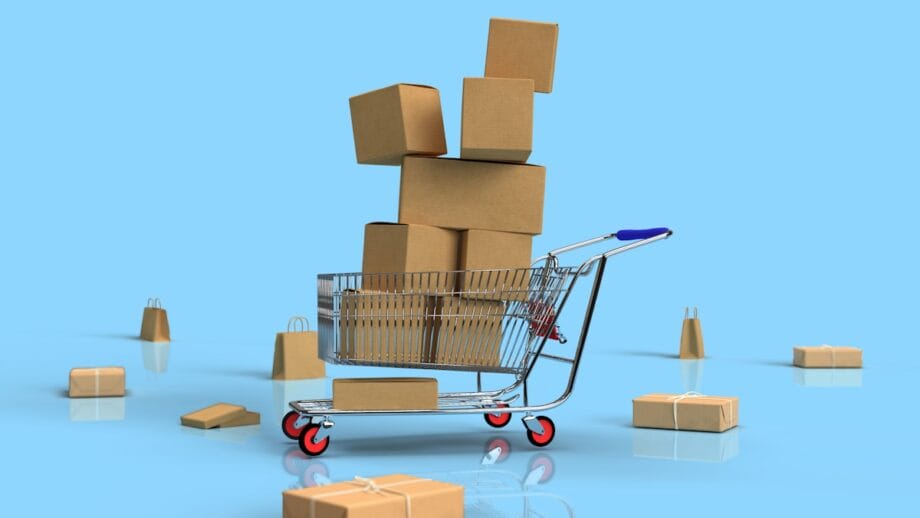 A shopping cart filled and stacked with cardboard boxes, surrounded by more boxes, on a blue background.