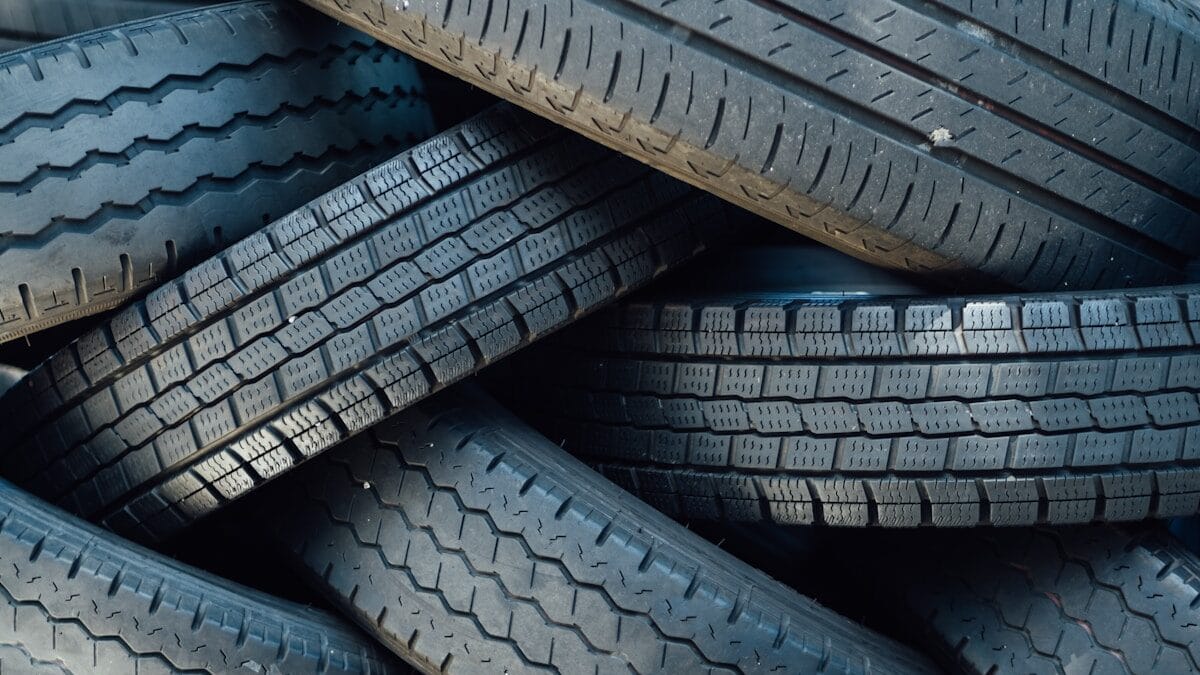 A pile of used black rubber car tires stacked irregularly, showing various tread patterns and some signs of wear.