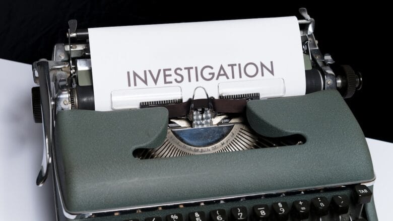 A typewriter with a sheet of paper displaying the word INVESTIGATION in large letters.
