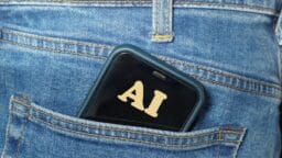 A smartphone with AI on its screen is partially visible in the back pocket of blue denim jeans.