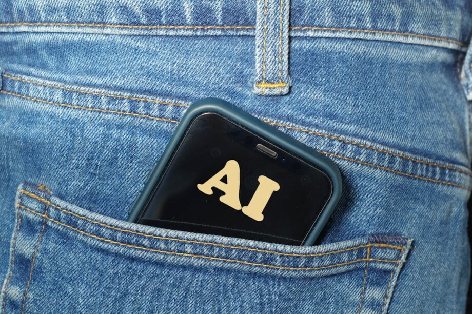 A smartphone with AI on its screen is partially visible in the back pocket of blue denim jeans.