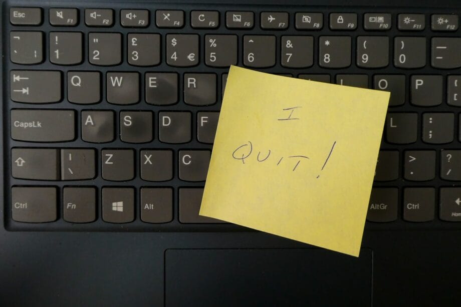 A yellow sticky note with I QUIT written on it is placed on a laptop keyboard.