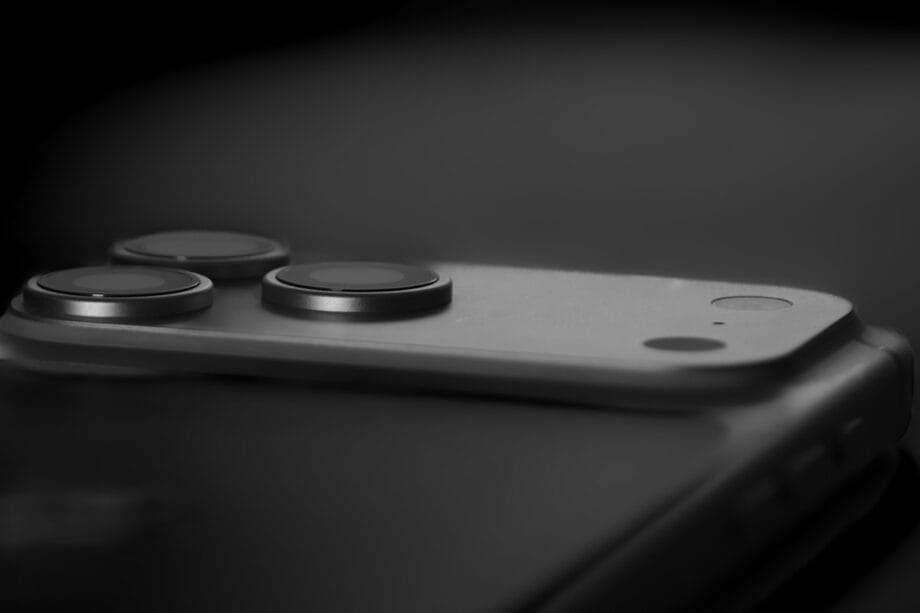 Close-up of a smartphone camera module with three lenses and a flash on a dark background.