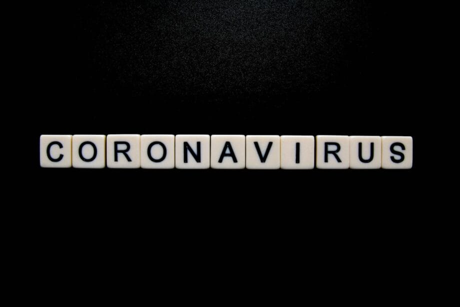 White letter tiles on a black background spell out the word CORONAVIRUS in uppercase letters.