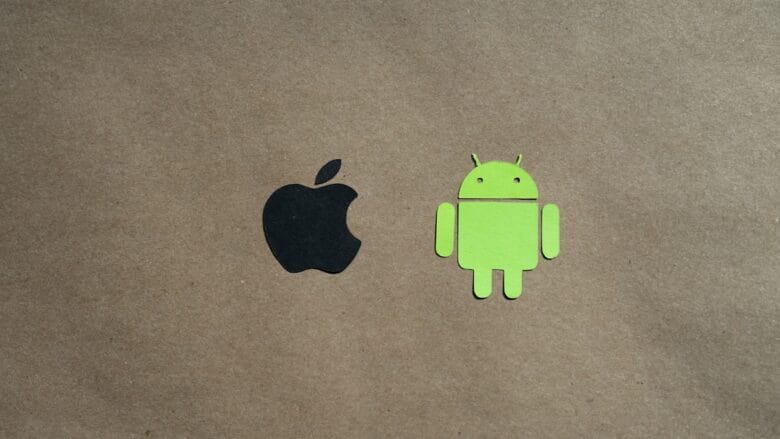 Black Apple logo and green Android robot logo on a plain brown background, centered side by side.