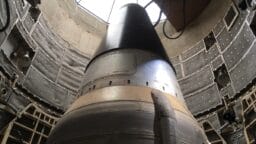 Close-up view of a missile inside an underground silo, surrounded by metal walls and equipment.