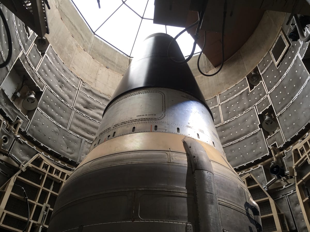 Close-up view of a missile inside an underground silo, surrounded by metal walls and equipment.