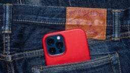 A smartphone with a red case is partially visible in the back pocket of blue denim jeans.