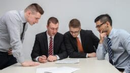 four men looking to the paper on table