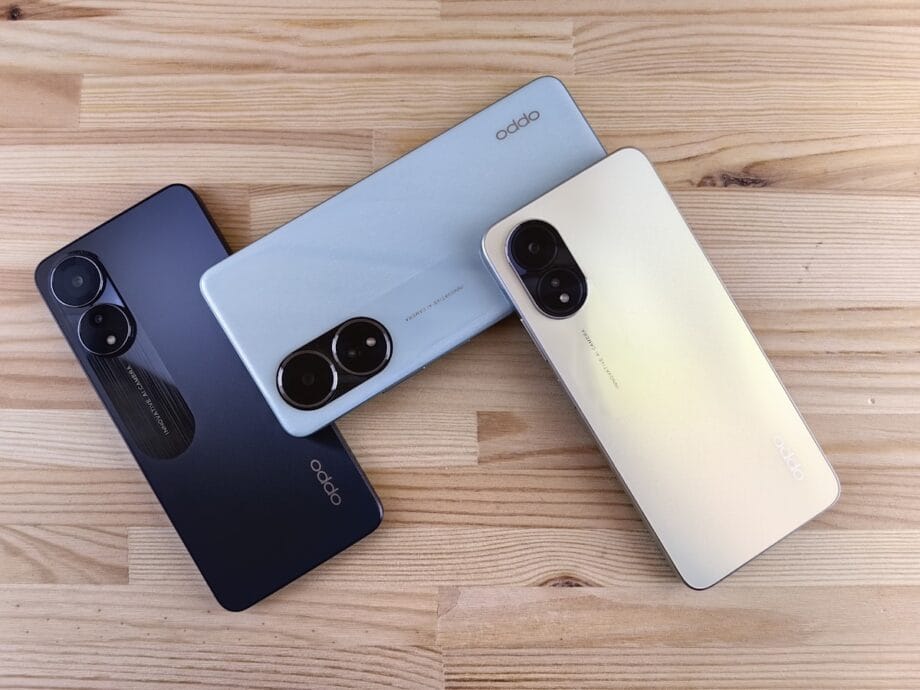 Three smartphones in different colors on a wooden surface