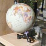 A small globe on a wooden stand displays Africa, Europe, and the South Atlantic Ocean under bright lighting.