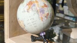 A small globe on a wooden stand displays Africa, Europe, and the South Atlantic Ocean under bright lighting.