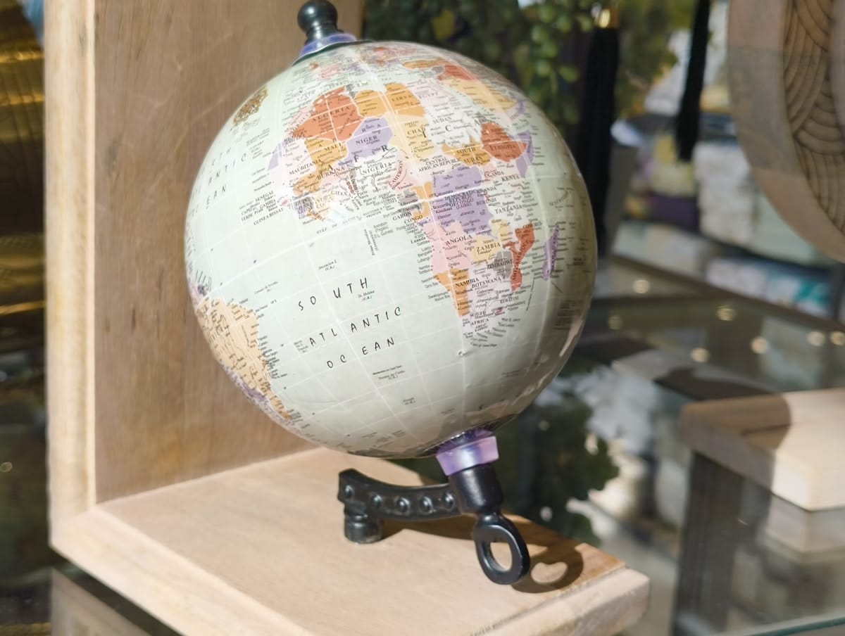 A small globe on a wooden stand displays Africa, Europe, and the South Atlantic Ocean under bright lighting.