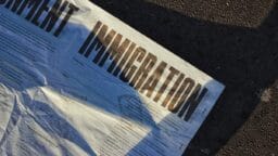 A close-up of a document on the ground with the word IMMIGRATION printed in bold letters.